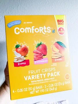 Hand holding a yellow box of Comforts Fruit Crisps Variety Pack freeze-drie.. Foto stock