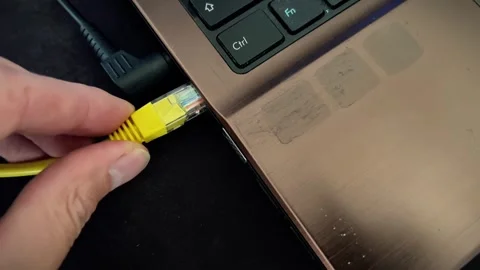 Hand Holding Yellow Ethernet Cable Near Laptop Port Close Up Stock Footage 348702374