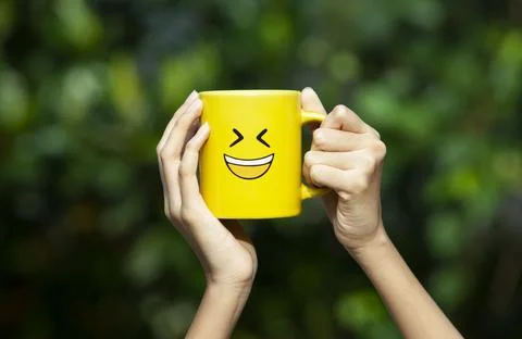 Hand holding yellow glass with smiley emoticon Stock Photos