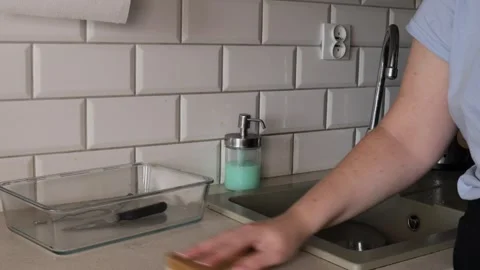 Hand holding a yellow sponge and wiping a smooth kitchen countertop surface.. Stock Footage 320737764