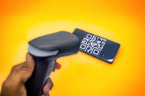 A hand holds a barcode scanner aimed at a smartphone displaying a QR code o.. Stock-Fotos