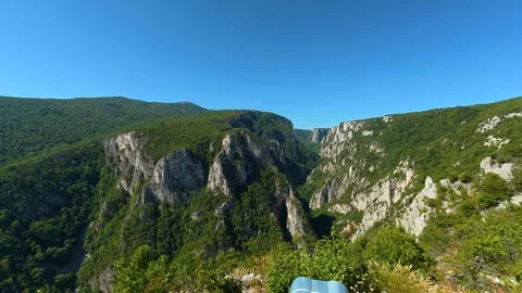 Hand holds binoculars, framing vast canyon vista. Lazar's Canyon, Serbia Stock Footage 345332584