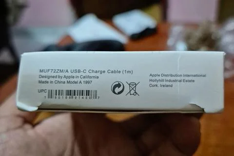 A hand holds the bottom panel of a white retail packaging box for USB-C cable Stock Photos