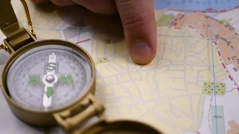 Hand holds brass compass above detailed map Stock Footage 314979345