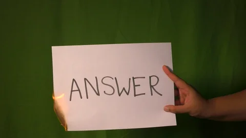 A hand holds the burning paper with answer word on it Stock Footage 127922104