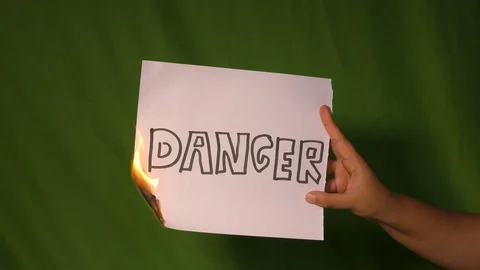 A hand holds the burning paper with danger text word on it on. Stock Footage 127921677