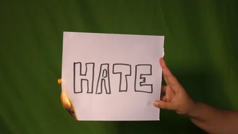 A hand holds the burning paper with hate text word on it. Stock Footage 127921735