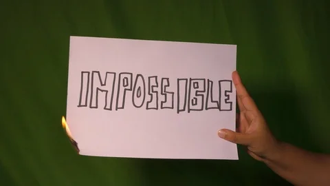 A hand holds the burning paper with impossible text word on it. Stock Footage 127921518