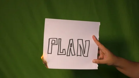 A hand holds the burning paper with plan text word on it. Stock Footage 127921778