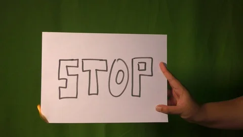 A hand holds the burning paper with stop divide text word on it. Stock Footage 127922144