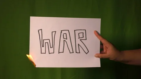 A hand holds the burning paper with war divide text word on it. Stock Footage 127922244