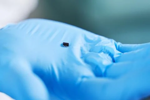 Hand holds chip compenent. Embedding the chip under human skin, microcontroll Foto stock