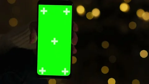 Hand holds Chroma Key Green Screen in vertical position at night on Christmas Stock Footage 219925176