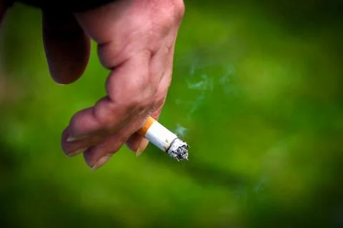 Hand holds cigarette between two fingers Stock Photos