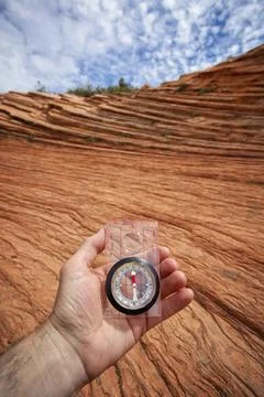 A hand holds a compass above wind-sculpted red sandstone in Zion National P.. Stock Photos