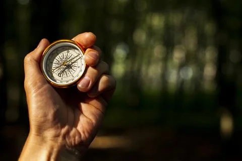 Hand holds compass with blurred background. High quality photo Stock Photos