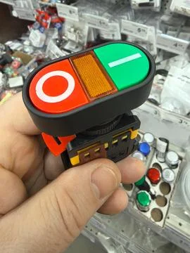 A hand holds a control switch with a red stop button and a green start button Stock Photos