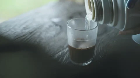 A hand holds a cup of coffee on a table with a spoon. Video stock 328031360