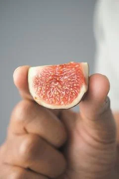 Hand holds a cut fig with inside showing details Stock Photos