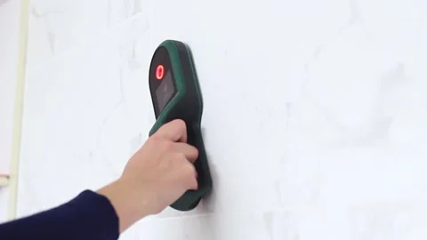 The hand holds a detector with the help of which it looks for cables with Stock-Footage 240931653