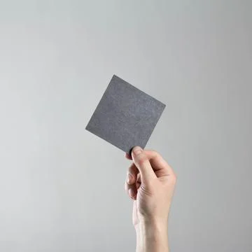 The hand holds an empty square black sheet of paper. A clean flyer in your ha Fotos Stock