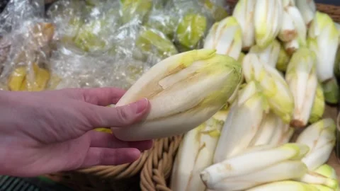 A hand holds an endive at a market Stock Footage 318078341