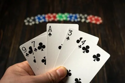 A hand holds five playing cards with an ace and numbers on them. Poker chip.. Foto stock