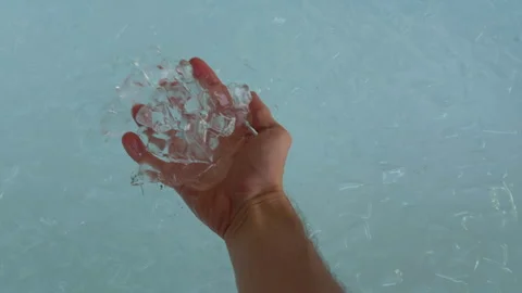 Hand Holds Ice Cubes Over a Bathtub Filled With Cold Water, Preparing Cryotherap Stock Footage 339602304