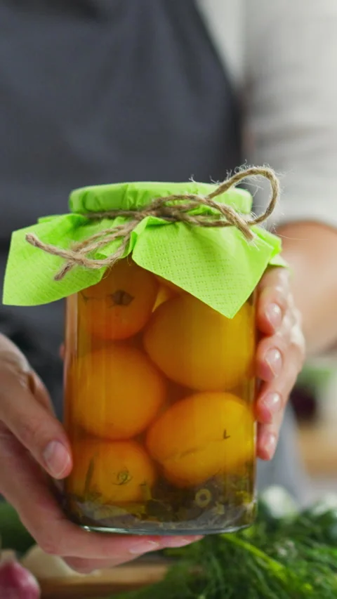 A hand holds a jar of pickled tomatoes freshly canned and ready to eat Stock Footage 331528552