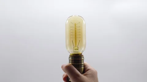 A hand holds a light bulb that switchs on and a few seconds later it switchs off Stock Footage 128829578