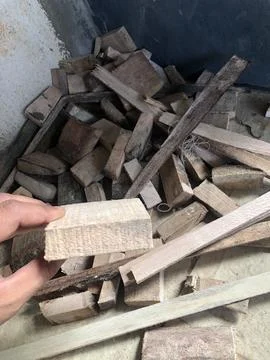 Hand holds light-colored rectangular piece of wood above a large pile of va.. Stock Photos