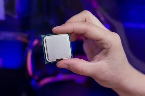 Hand holds a modern processor. Computer with RGB illumination in background.  스톡 사진