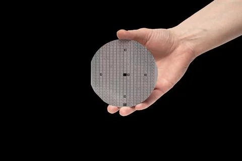 A hand holds multilayer semiconductor silicon wafer with a microcircuit chip Stock Photos