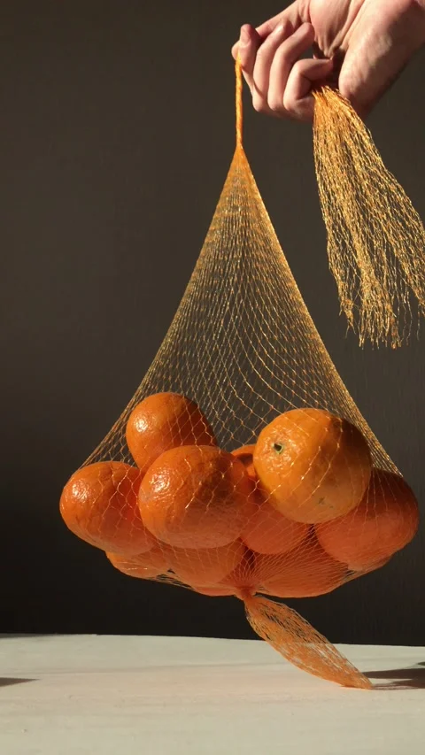 Hand holds a net with tangerines Stock Footage 172562899