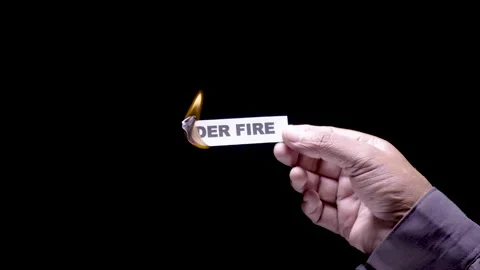 Hand Holds Paper Burning the words Under fire Stock Footage 248535256