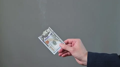 A hand holds a paper item as smoke rises from it in four frames. Stock Footage 338300028