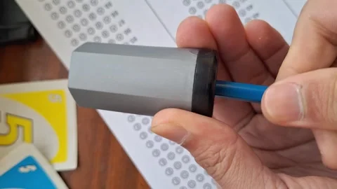 Hand holds pencil sharpener with blue pencil Stock Footage 330759999