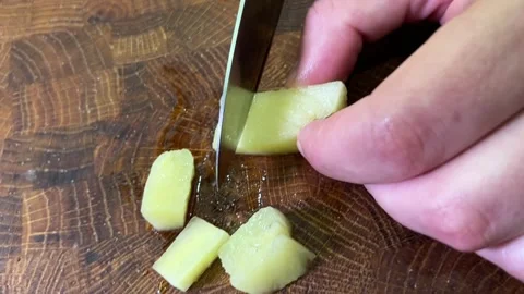 A hand holds a pickled cucumber while a kitchen knife cuts it into small pi.. Stock Footage 346166263