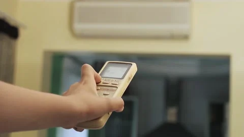 Hand holds the remote control and turns on the air conditioner at home Stock Footage 201165141