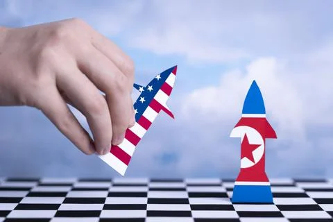 Hand holds a rocket with the US flag pointing towards a rocket figurine with  Stock-Fotos