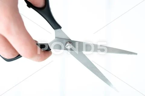 The hand holds the scissors for thinning out on an isolated white background Stock Photos