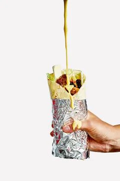 The hand holds the shawarma with the stuffing, which is poured with cheese sa Stock Photos