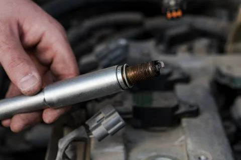The hand holds the spark plug. Stock Photos
