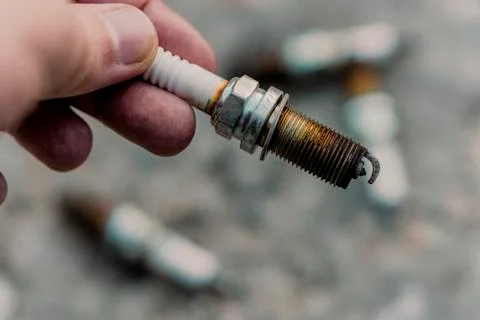 The hand holds the spark plug. Stock Photos