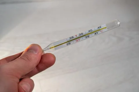 A hand holds a thermometer with high temperature Stock Photos