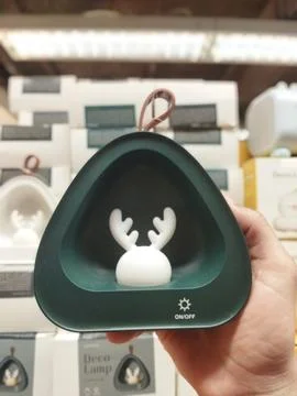 A hand holds a triangular, deep green nightlight with a clear front. Foto stock