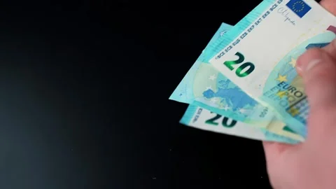 Hand holds twenty euro notes on a dark background with copy space, illustrating Vídeo Stock 328871058