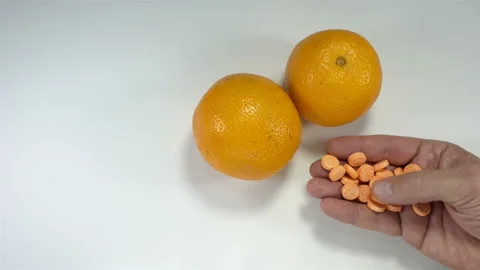Hand holds vitamins next to oranges fruit in 4K Stock Footage 142958745