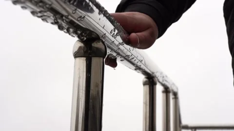 A hand holds onto a wet chrome-plated metal handrail outside Stock Footage 152829057