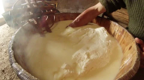 Hand in hot fermented sheep's milk collects large lump of cheese in bucket Stock Footage 43224649